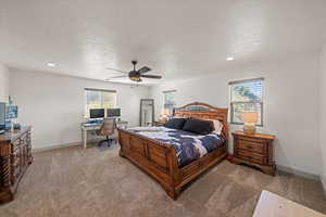 Carpeted bedroom with ceiling fan, multiple windows, and a textured ceiling