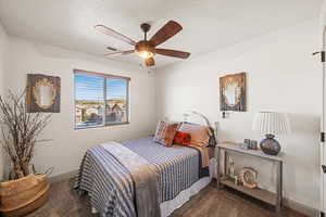 Carpeted bedroom with ceiling fan and a textured ceiling