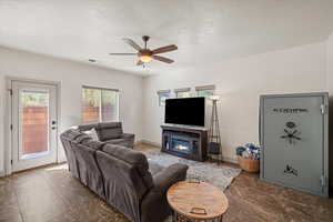 Living room with a textured ceiling, ceiling fan, and a fireplace