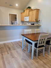 Dining space with washer and dryer, sink, light wood-type flooring, and vaulted ceiling