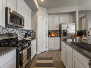 Kitchen featuring hardwood / wood-style floors, stainless steel appliances, white cabinetry, and sink