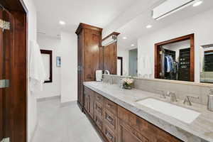 Primary Bathroom featuring vanity with Marble Countertops and a decorative backsplash, and travertine tile flooring