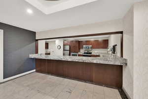 Common Area Social Room Kitchen with sink, light stone countertops, kitchen peninsula, and appliances with stainless steel finishes