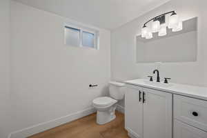 Bathroom featuring toilet, vanity, and hardwood / wood-style flooring