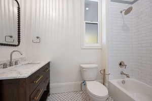 Full bathroom with vanity, tile patterned floors, tiled shower / bath, and toilet