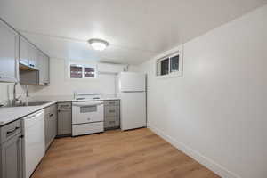 Kitchen with light hardwood / wood-style floors, sink, a wall unit AC, white appliances, and gray cabinetry