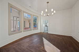 Unfurnished dining area featuring parquet flooring and a chandelier