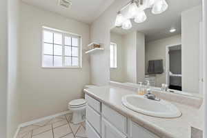 Full Bathroom with toilet, vanity, an inviting chandelier, and tile patterned flooring