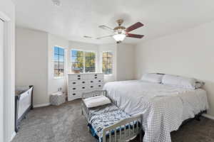 Master bedroom with ceiling fan and a textured ceiling