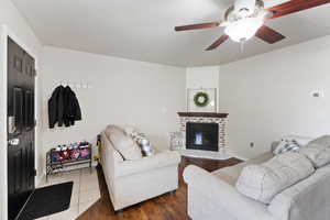 Living room with wood-type flooring, ceiling fan, and a fireplace