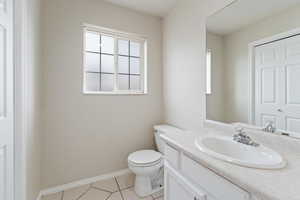 1/2 Bathroom with toilet, vanity, and tile patterned floors