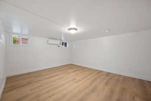 Interior space with light wood-type flooring and an AC wall unit