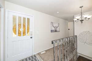 Foyer featuring an inviting chandelier and carpet floors