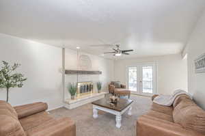 Living room with french doors, light colored carpet, ceiling fan, and a fireplace