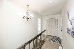 Hall with a chandelier, a textured ceiling, and carpet