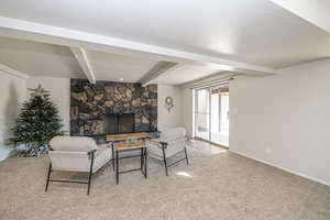 Carpeted living room featuring a fireplace, beamed ceiling, and a textured ceiling, walk-out patio