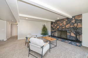 Carpeted living room featuring beamed ceiling, a textured ceiling, and a fireplace