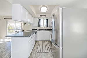 Kitchen with stainless steel appliances, light wood-type flooring, white cabinetry, backsplash, and kitchen peninsula