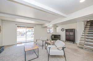 Carpeted living room featuring beamed ceiling and a textured ceiling