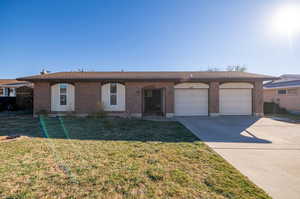 Single story home featuring a garage and a front yard