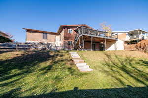 Back of property featuring a yard and a wooden deck