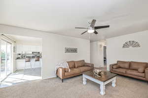 Living room light colored carpet, and ceiling fan