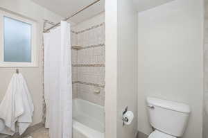 Bathroom featuring shower / bath combo, tile patterned flooring, and toilet