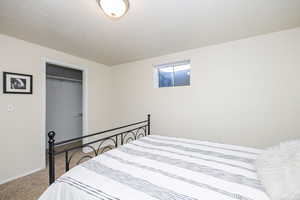 Carpeted bedroom featuring a textured ceiling and a closet