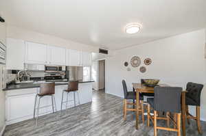 Kitchen with stainless steel appliances, light hardwood / wood-style floors, white cabinets, decorative backsplash, and sink