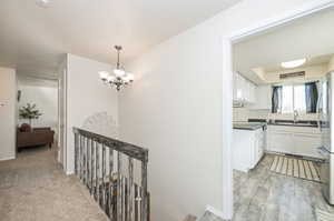 Entry way Hall featuring light colored carpet, kitchen entry, and an inviting chandelier