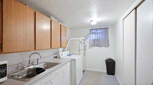 Laundry room with a textured ceiling, sink, and washer / clothes dryer