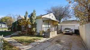 View of property exterior with a garage, an outdoor structure, and a lawn