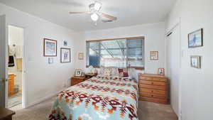 Carpeted bedroom featuring ensuite bathroom and ceiling fan