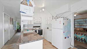 Kitchen featuring white cabinetry, sink, dark stone countertops, independent washer and dryer, and white appliances