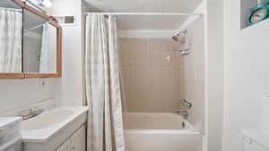 Full bathroom with shower / bath combo, vanity, a textured ceiling, and toilet