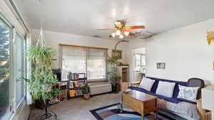 Living room with ornamental molding, a wealth of natural light, ceiling fan, and light colored carpet