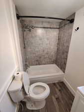 Full bathroom featuring vanity, a textured ceiling, tiled shower / bath combo, hardwood / wood-style flooring, and toilet