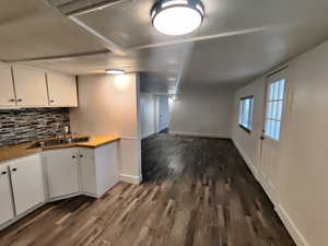 Kitchen featuring dark hardwood / wood-style flooring, backsplash, white cabinetry, and sink