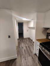 Kitchen featuring light hardwood / wood-style flooring, white cabinets, and stainless steel range with gas stovetop