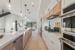 Kitchen with white cabinetry, appliances with stainless steel finishes, sink, and hanging light fixtures