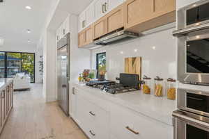 Kitchen with white cabinets, stainless steel appliances, a wealth of natural light, and light wood-type flooring