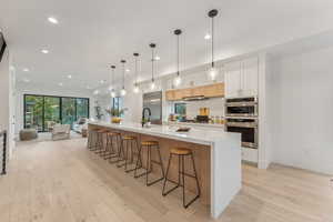 Kitchen featuring white cabinetry, pendant lighting, a large island, and stainless steel appliances