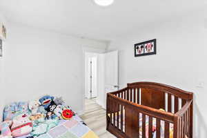 Bedroom featuring a nursery area and light hardwood / wood-style flooring