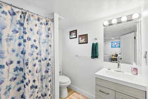 Bathroom featuring toilet, hardwood / wood-style floors, a textured ceiling, a shower with curtain, and vanity