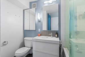 Bathroom featuring walk in shower, vanity, toilet, and backsplash