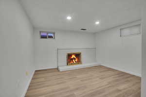 Unfurnished living room with a brick fireplace and light hardwood / wood-style floors