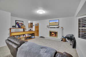 Living room featuring a textured ceiling, light colored carpet, and a brick fireplace