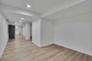 Basement featuring light hardwood / wood-style floors and stainless steel refrigerator