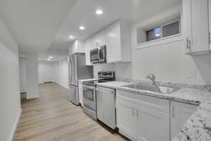 Kitchen featuring white cabinetry, light wood-type flooring, stainless steel appliances, and sink