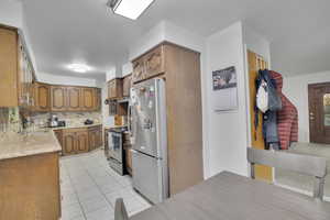 Kitchen featuring backsplash, sink, light tile patterned floors, and stainless steel appliances